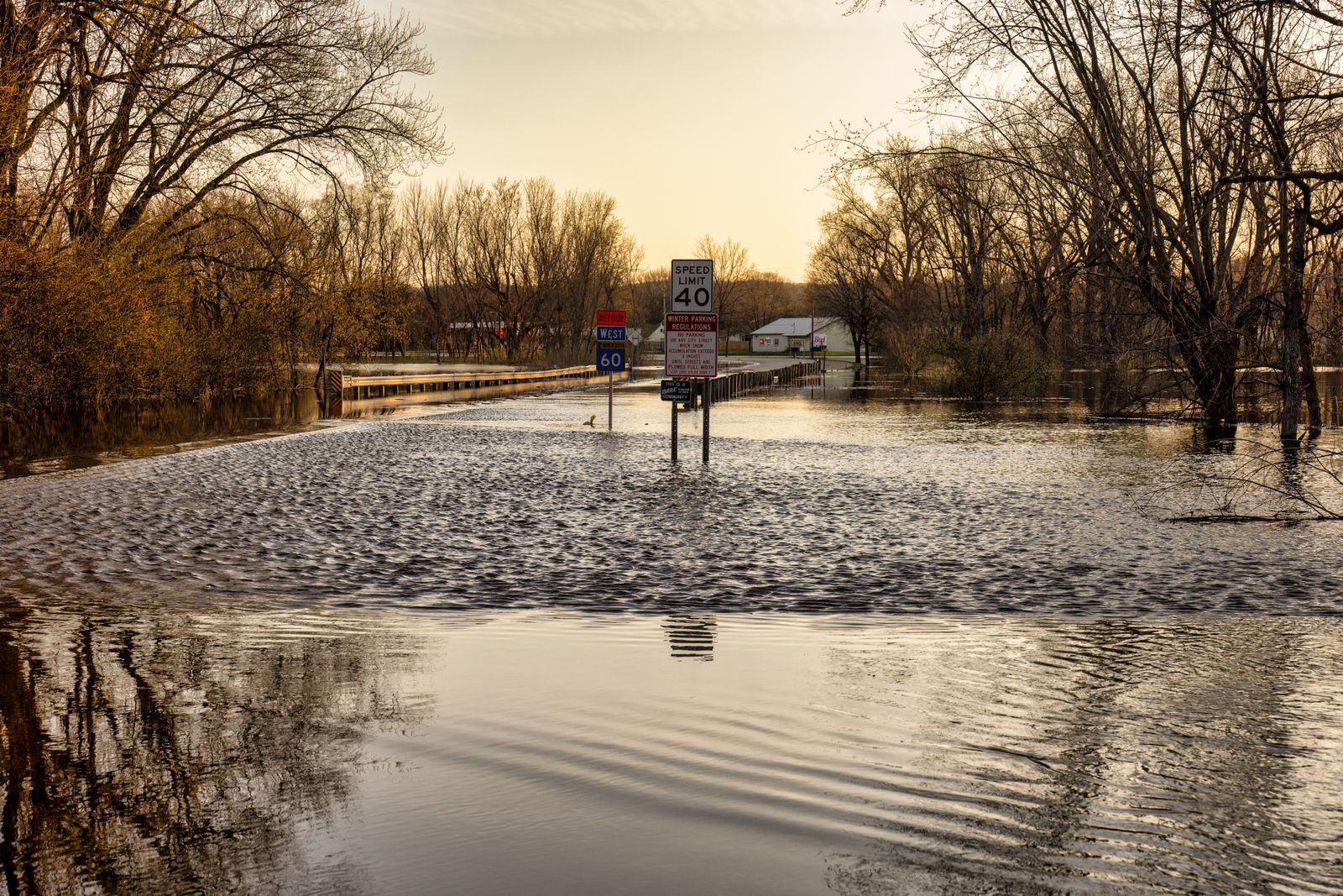 A flooded road with road signs standing in high water