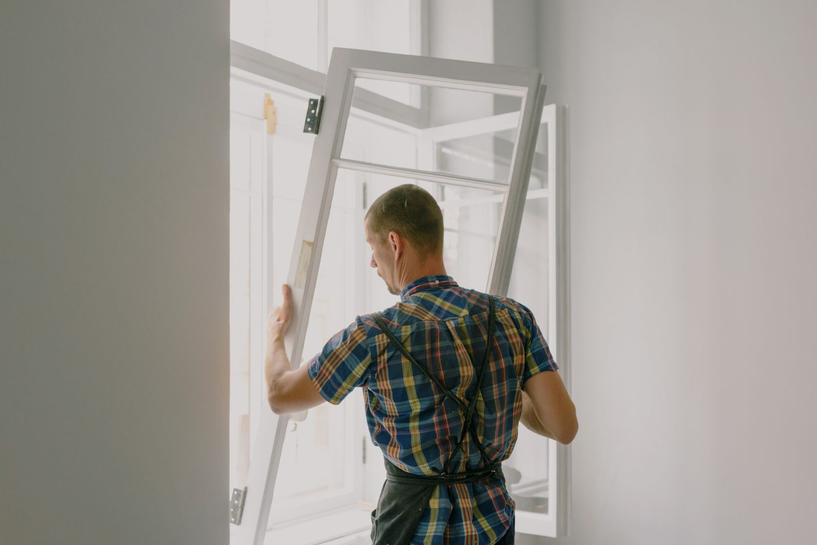 Installer fitting a new window unit into an opening during a home window replacement