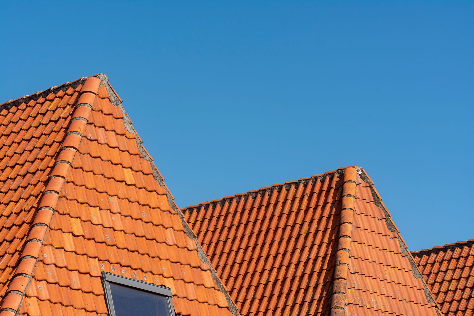Close-up of a tiled residential roof under a clear blue sky