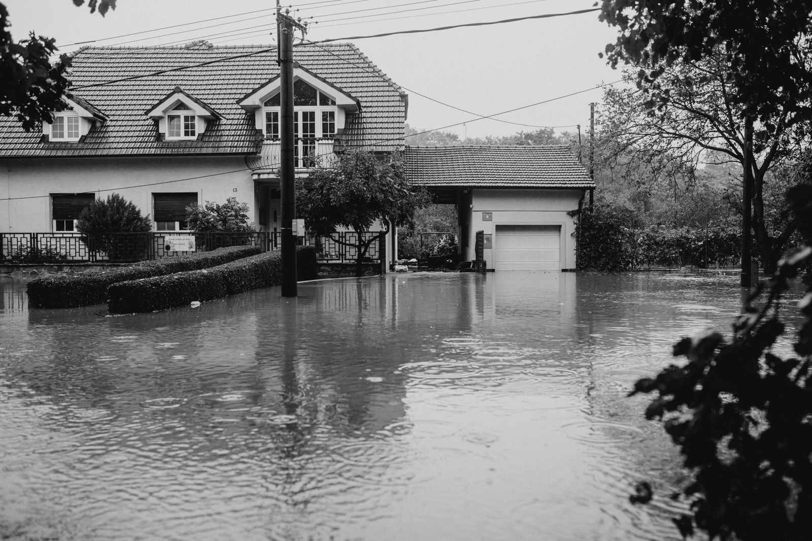 A suburban house surrounded by high floodwater, in black and white