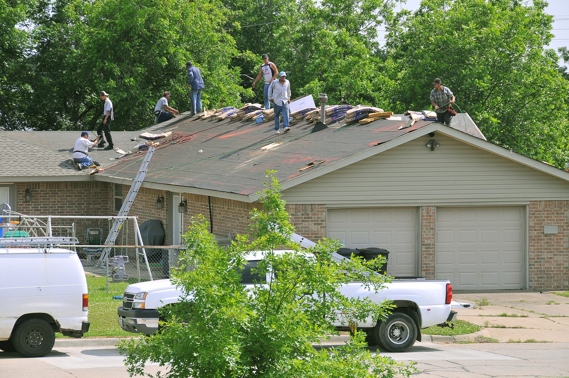 Roofing crew replacing shingles on a house roof