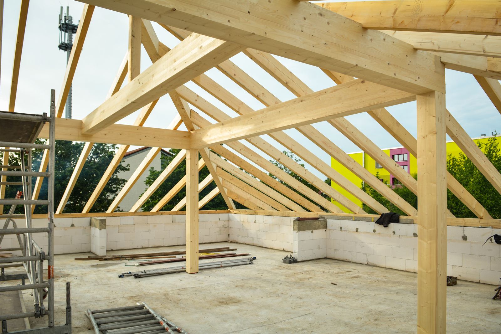 Interior view of a wooden roof frame with rafters resting on a low wall during home construction
