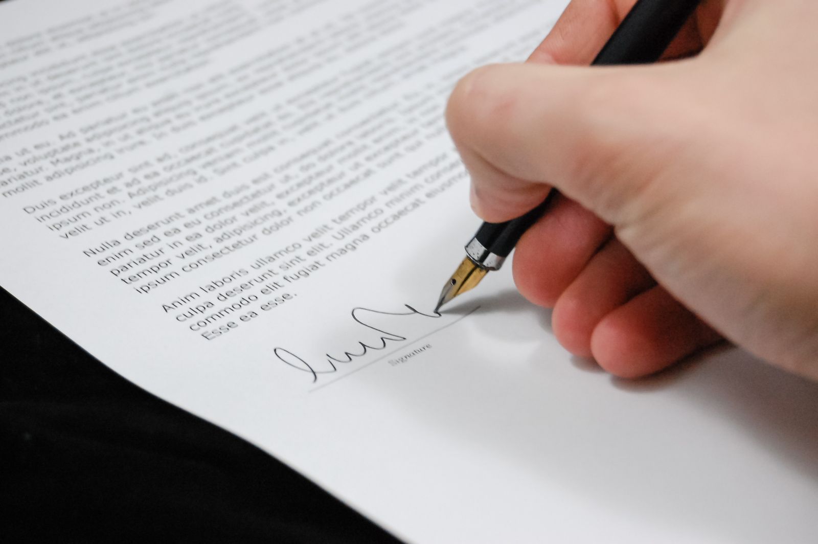 A homeowner signing a flood insurance policy document with a fountain pen