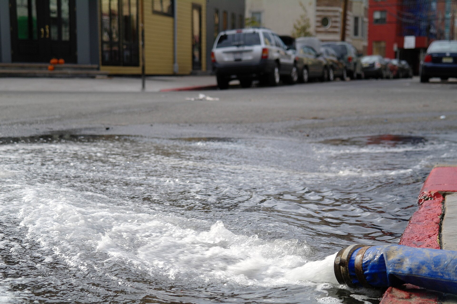 A pump discharge hose pushing water out onto a residential street